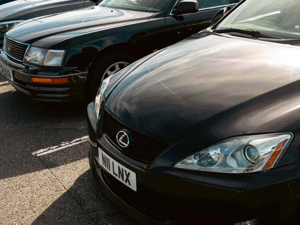 Black Lexus IS parked nose-to-nose with a dark green Lexus LS