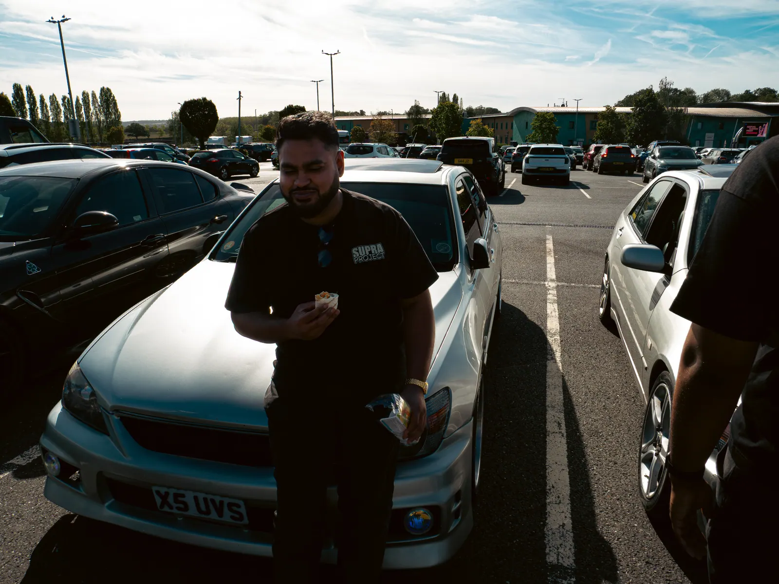 Leaning on the bonnet of a silver Lexus IS
