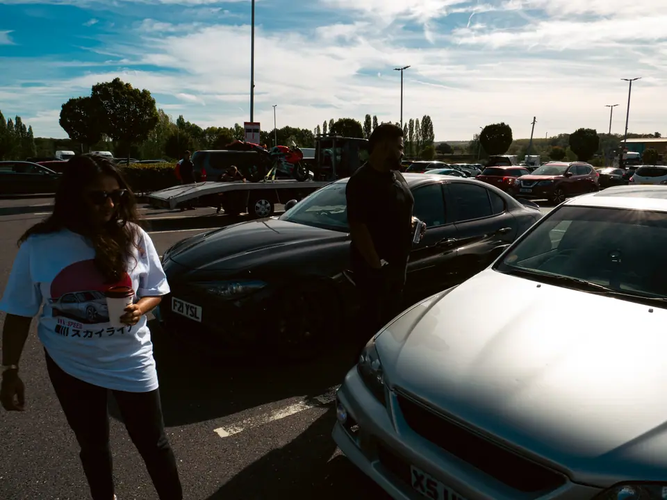 Walking between parked cars, a silver Lexus IS in front