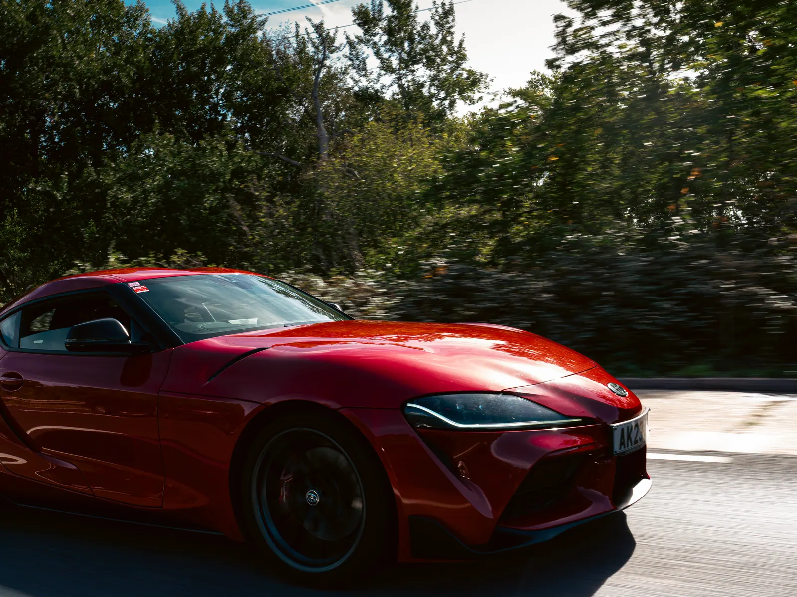 Red Toyota GR Supra on the move past a blur of trees