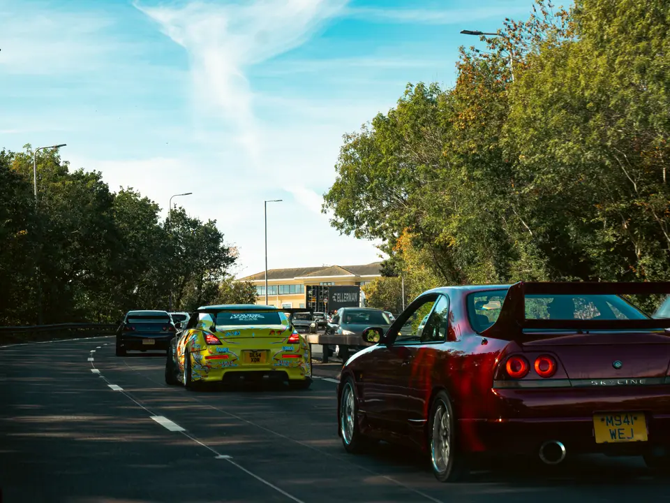 Red Nissan Skyline with a rear wing, in the convoy queue