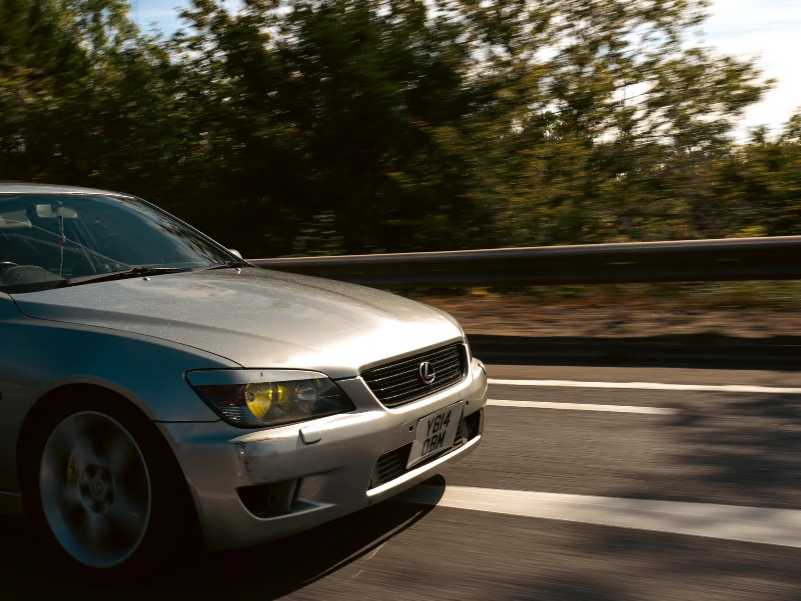 Silver Lexus IS with yellow fog lights, close rolling shot