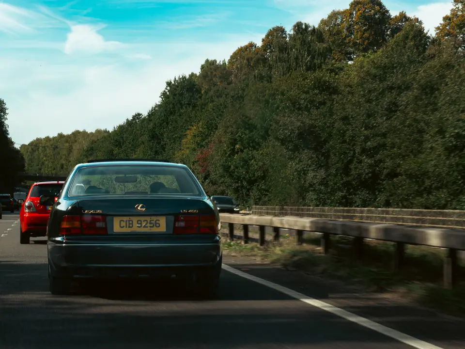 Dark green Lexus LS from behind, convoy stretching ahead