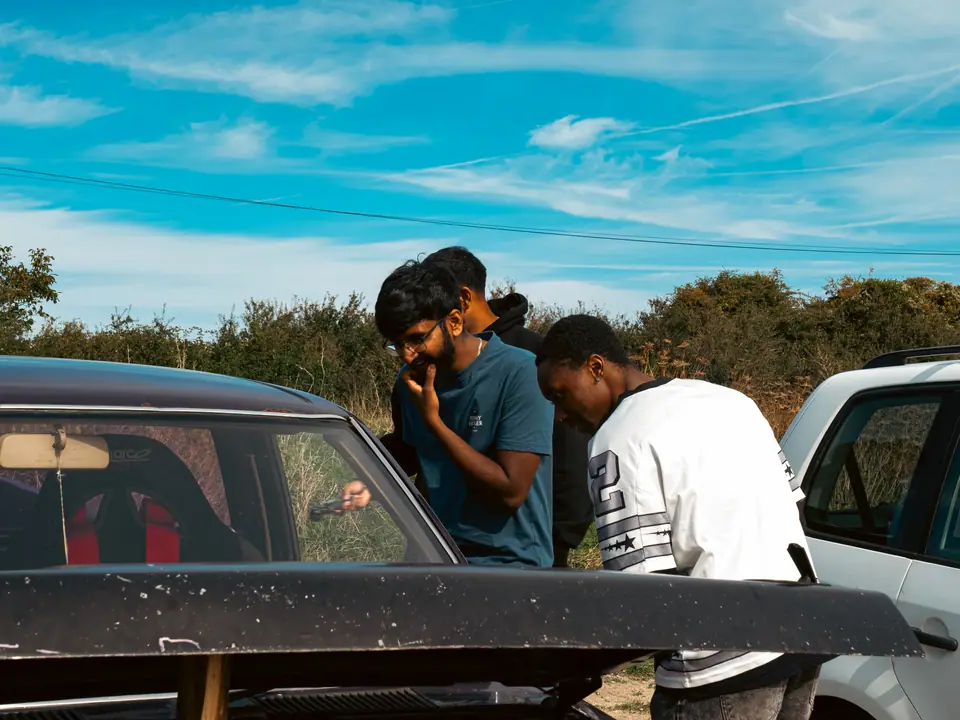 Friends gathered behind the open bonnet of the pick-up