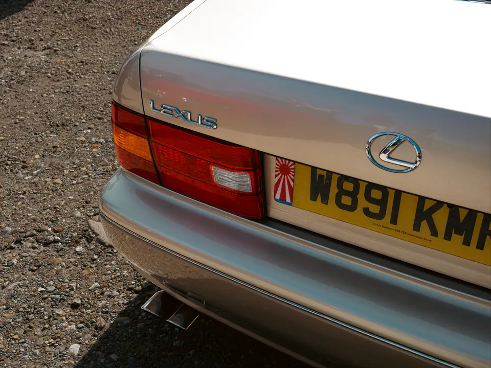 Rear badge and twin exhaust tips of a gold Lexus LS