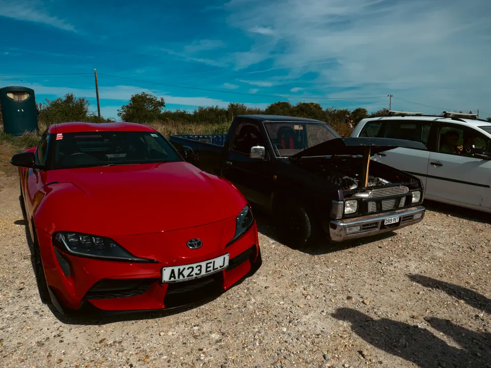 Red Toyota GR Supra parked next to the pick-up on the gravel