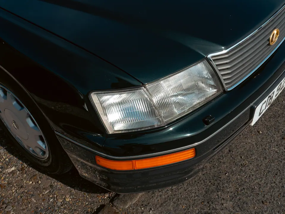 Headlight and chrome grille of a dark green Lexus LS