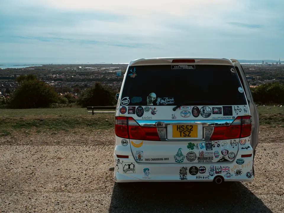 White Toyota Alphard covered in stickers, overlooking the harbour