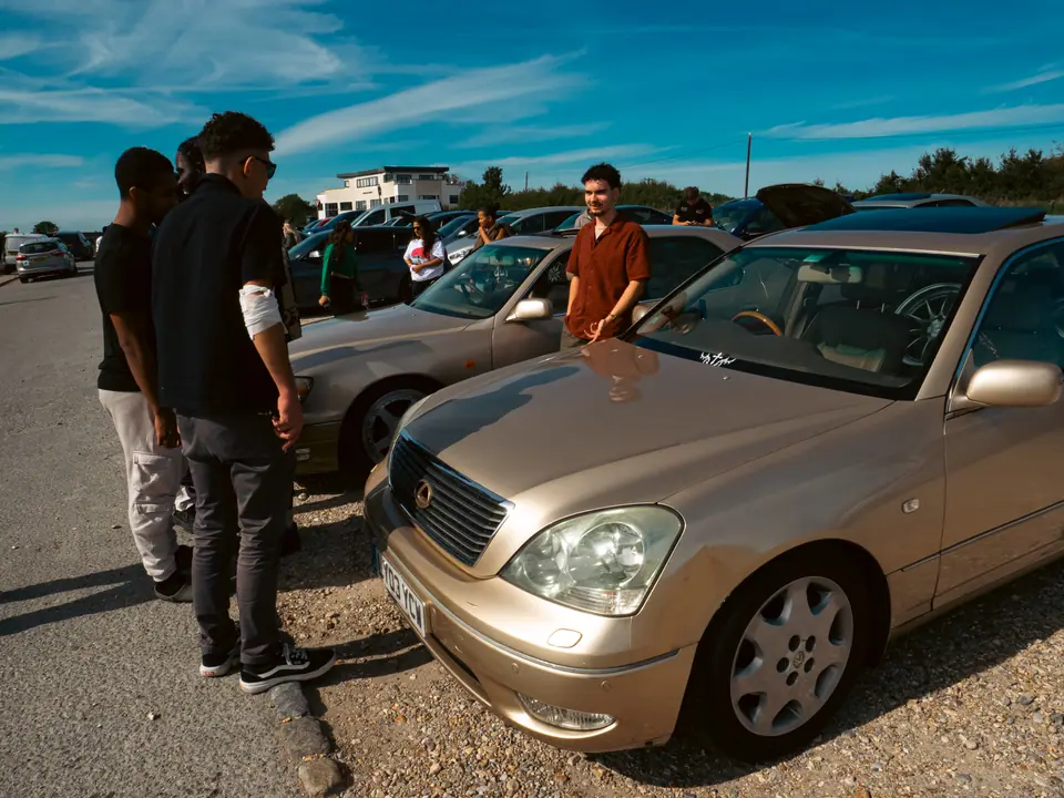 Gold Lexus LS with friends gathered around