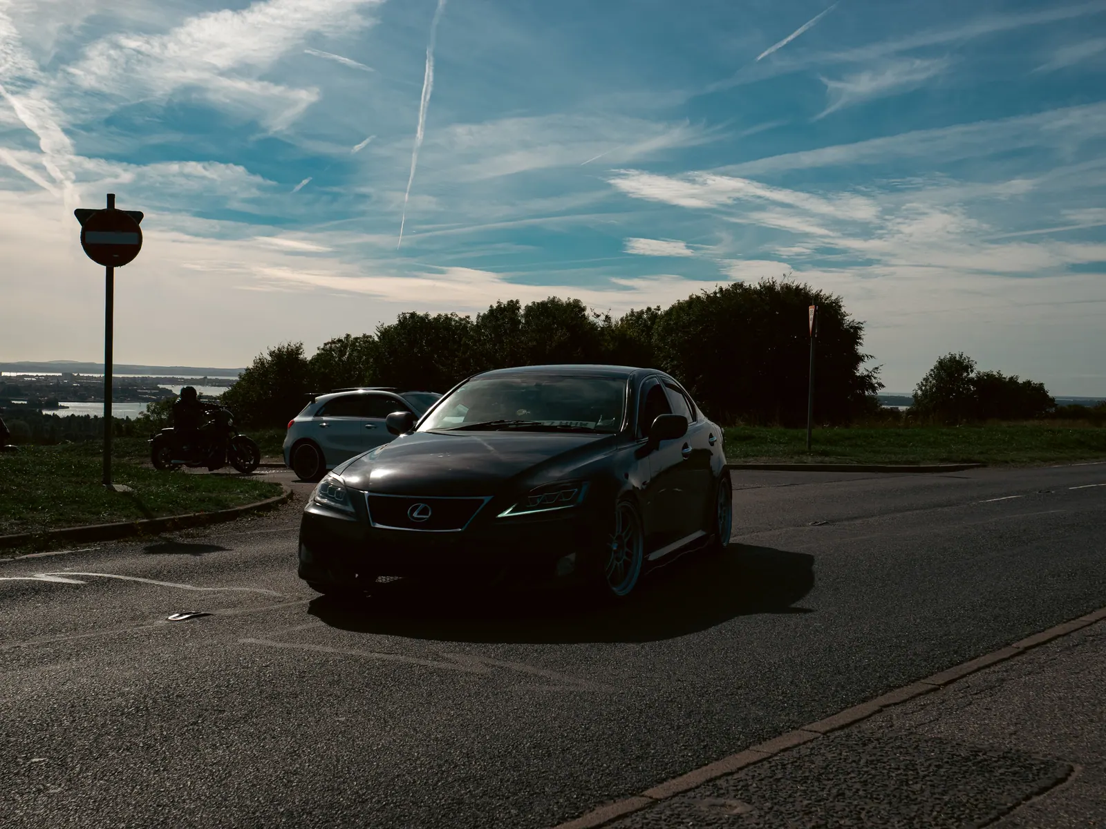 Black Lexus IS with a motorcycle behind