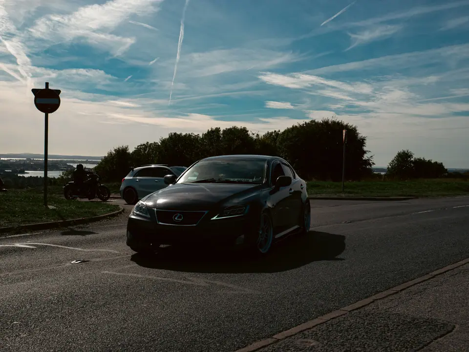 Black Lexus IS with a motorcycle behind