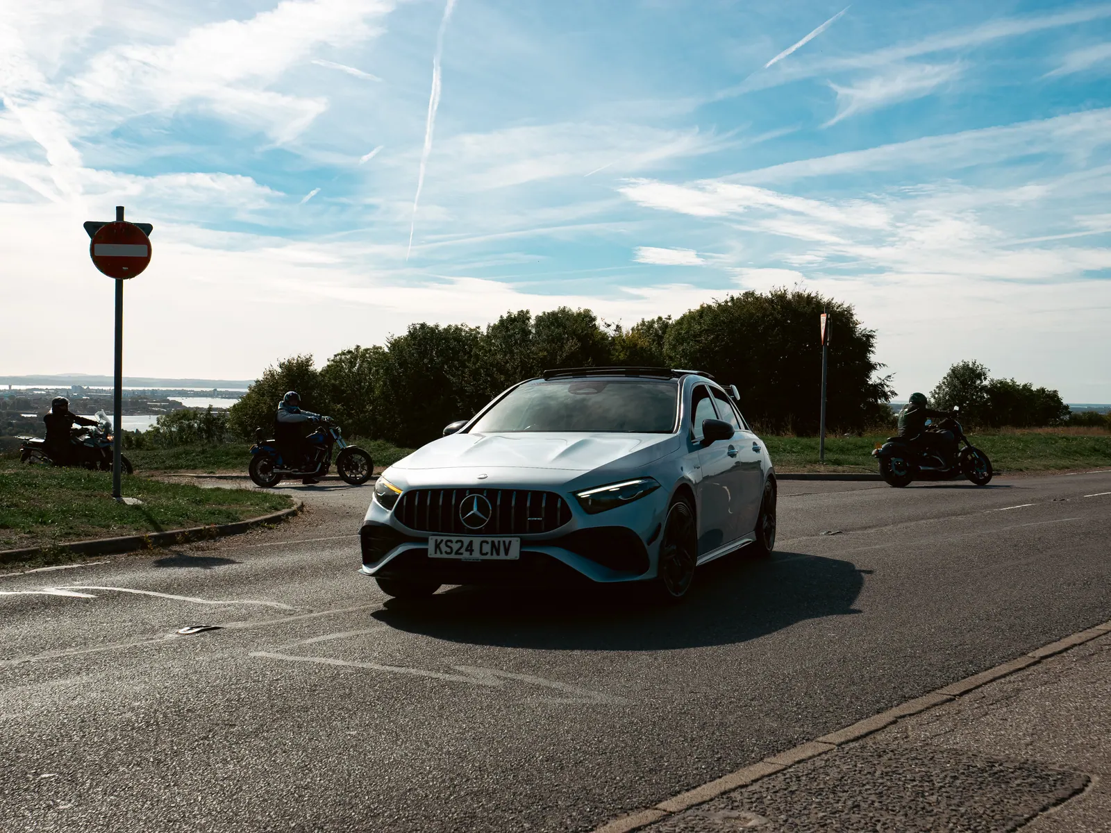 Silver Mercedes-AMG A-Class flanked by motorcycles