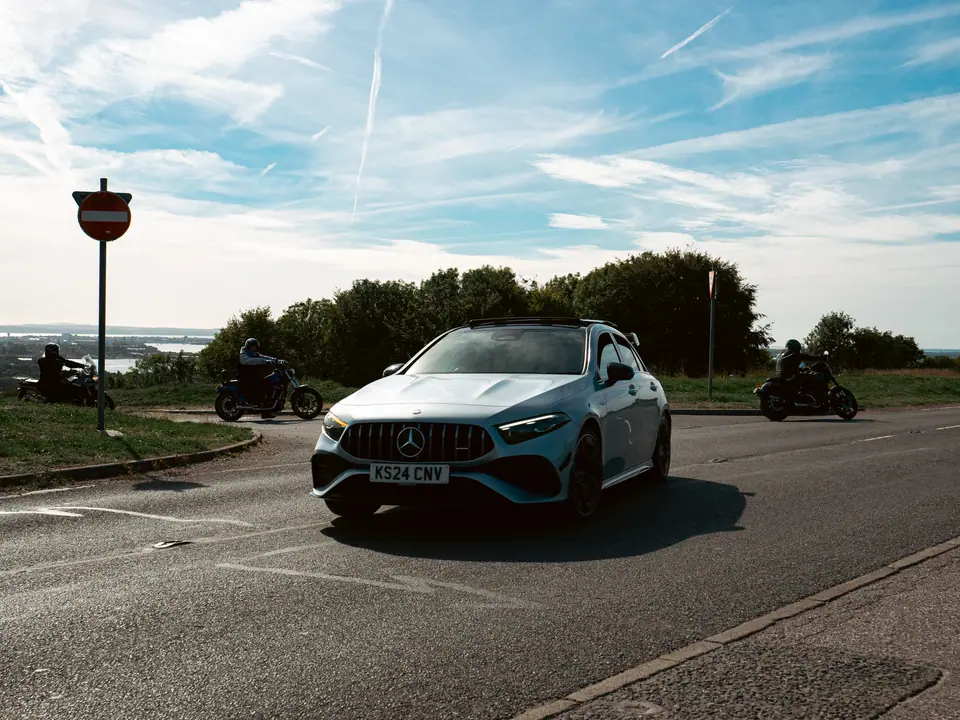 Silver Mercedes-AMG A-Class flanked by motorcycles