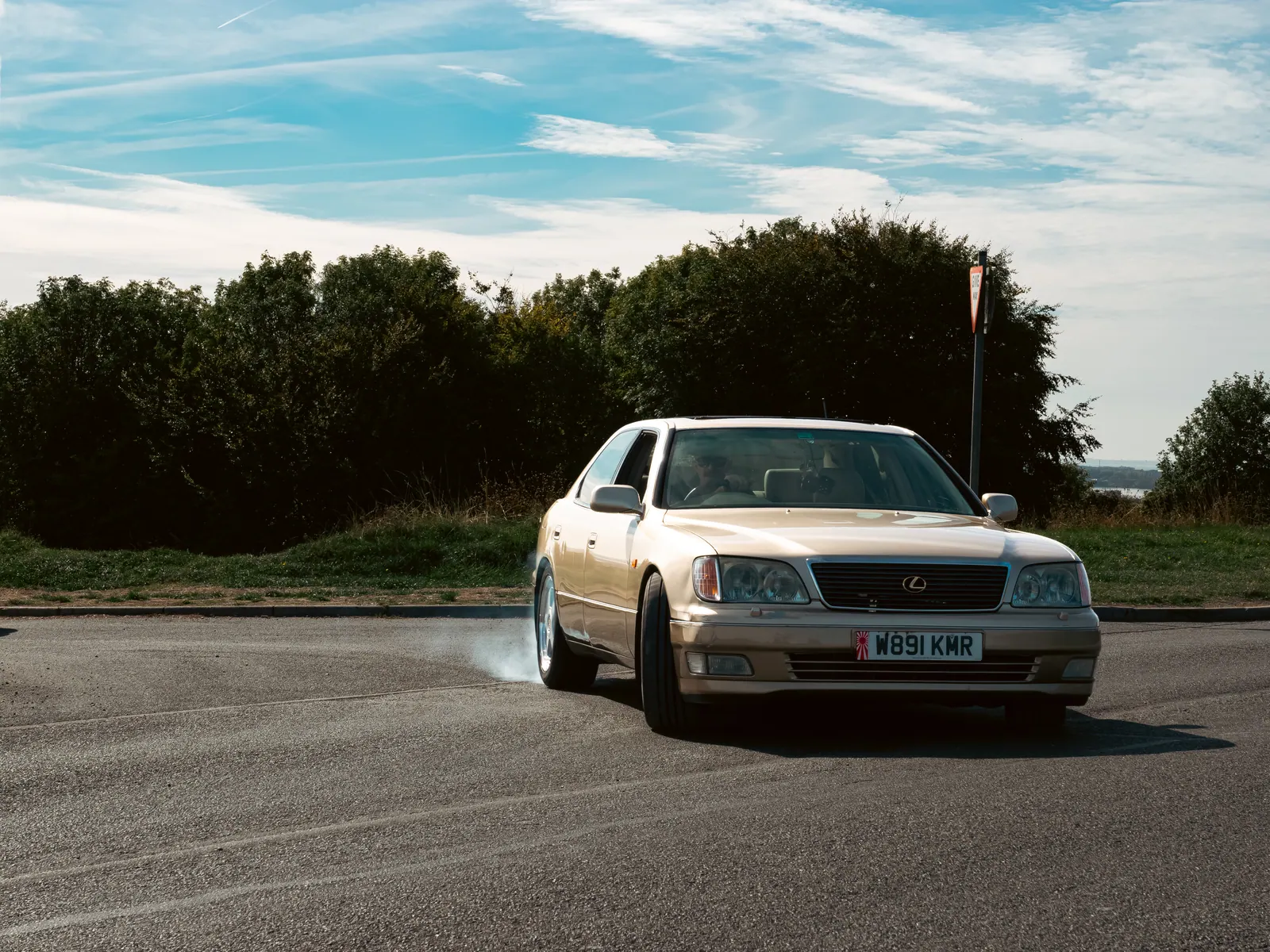 Gold Lexus LS pulling away with a puff of tyre smoke