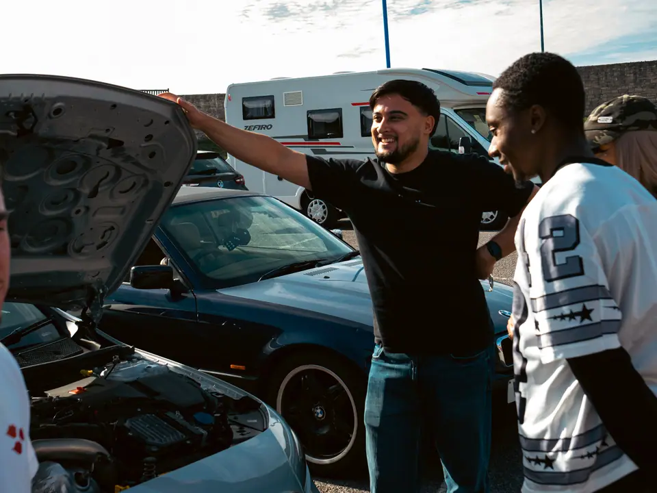 Chatting beside the open bonnet of the dark blue BMW