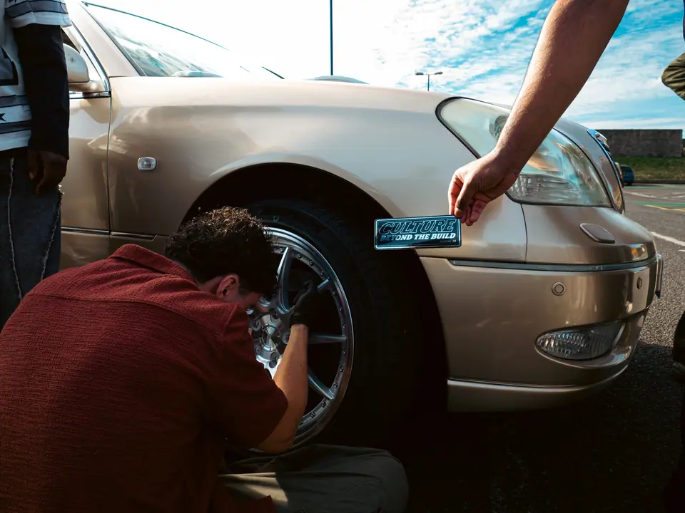 Wheel going on the gold Lexus LS, sticker in hand