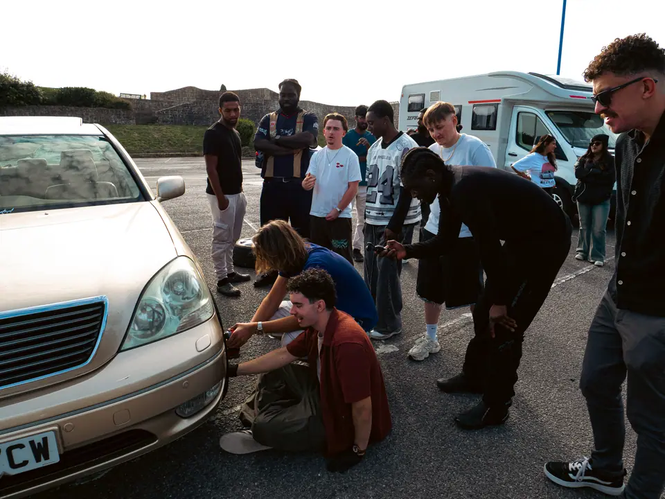 Crowd watching the wheel swap on the gold Lexus LS