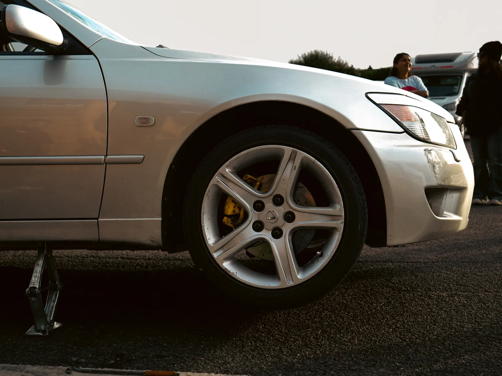 Silver Lexus IS on a jack, yellow brake calipers showing