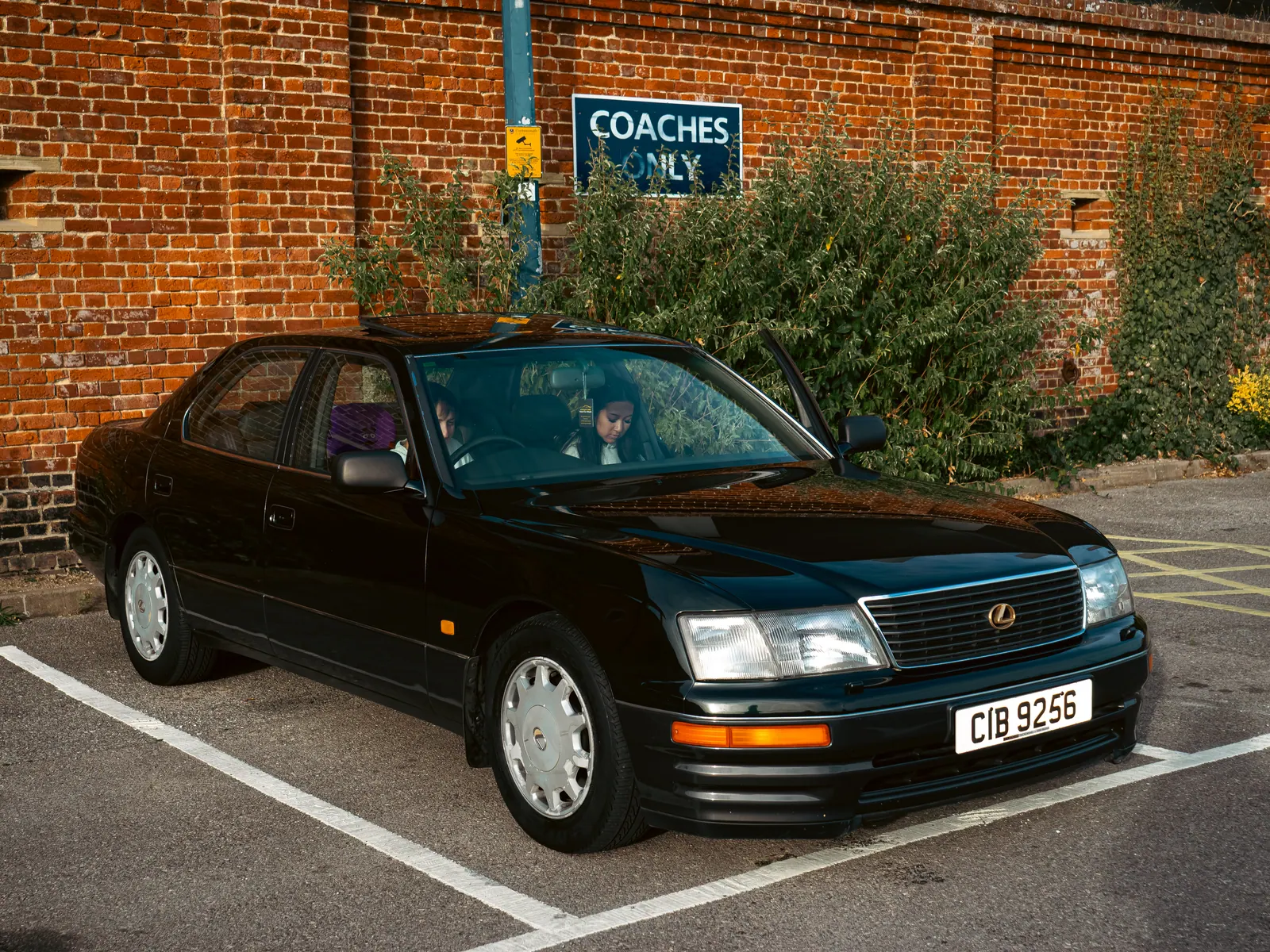 Dark green Lexus LS parked by the brick wall