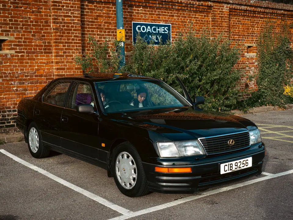 Dark green Lexus LS parked by the brick wall