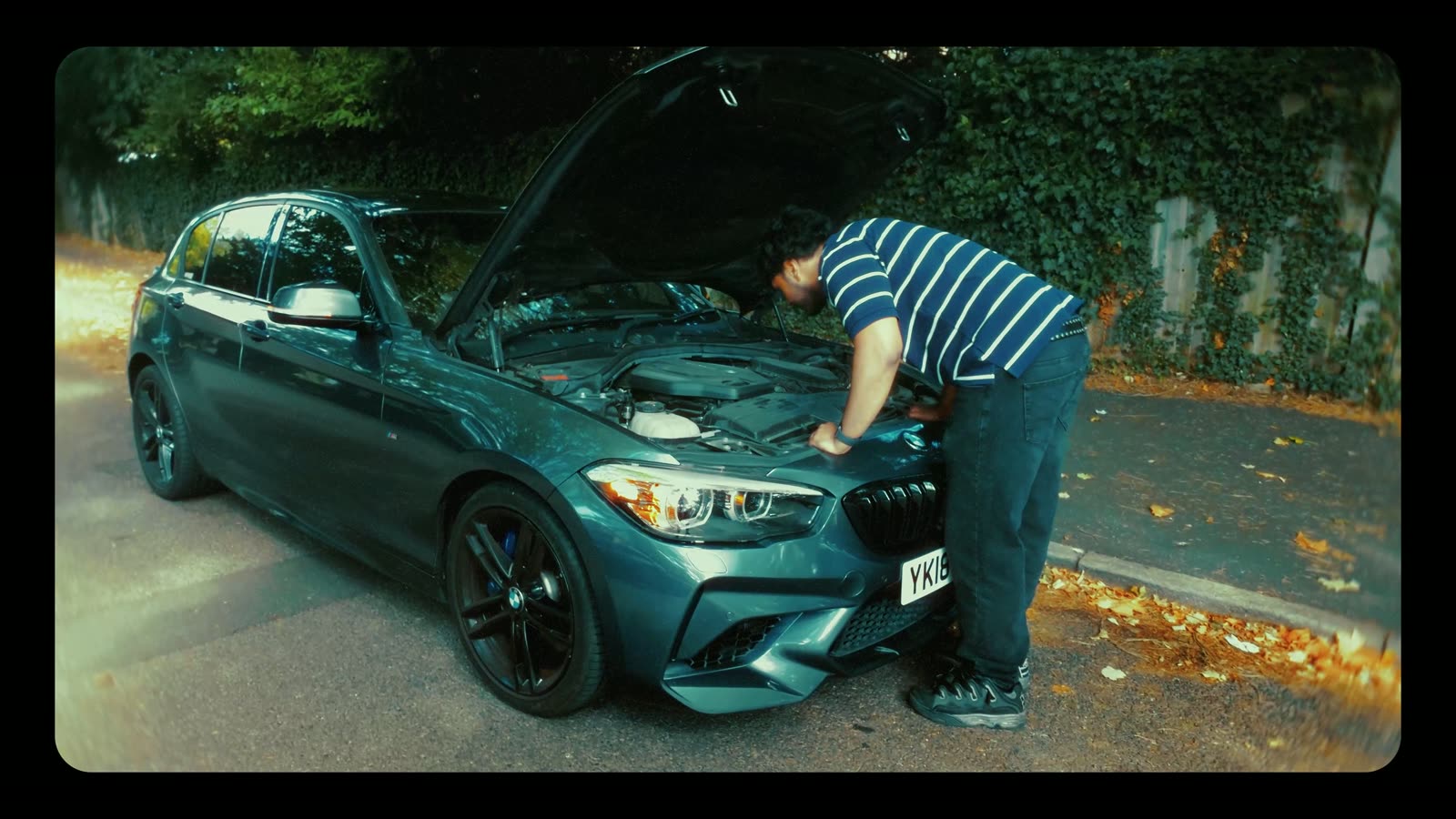 Teaser film: a grey BMW 1 Series being prepped on a leafy street before the cruise